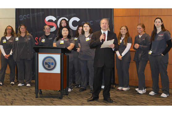 Dr. Michael Ash speaks with students behind him