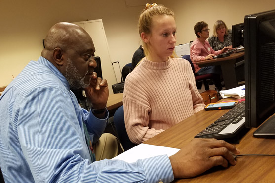 Instructor helps a student on a computer 