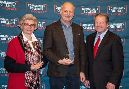 Two men and one woman posing with award